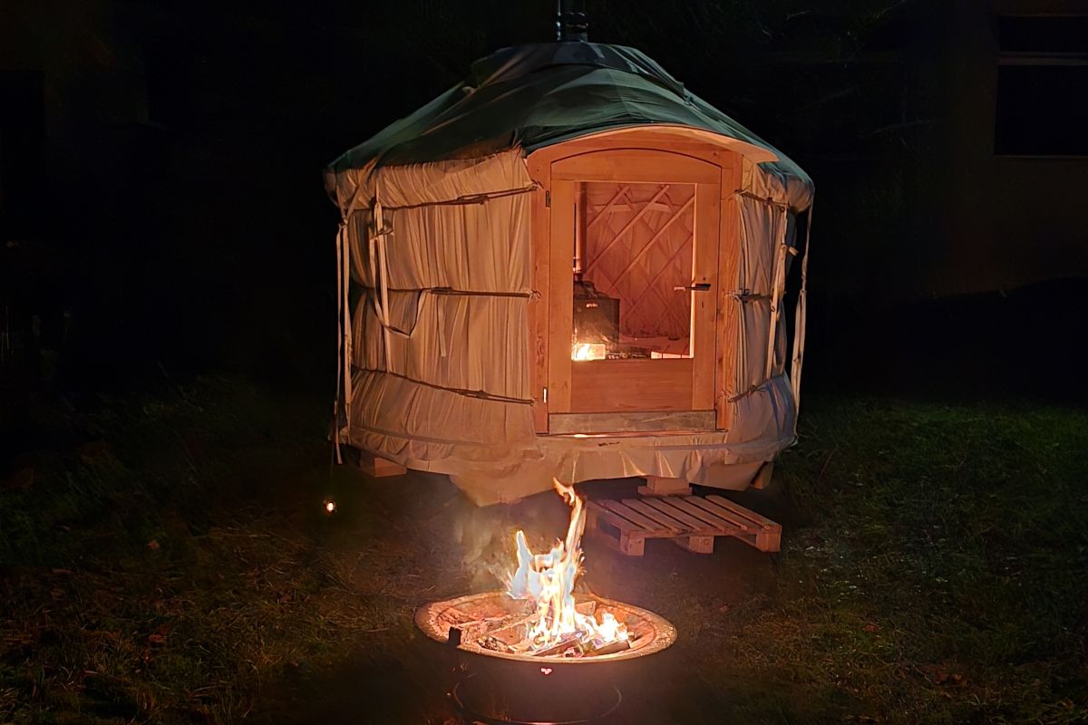 Saunajurte bei Nacht mit Feuerstelle vor dem Eingang