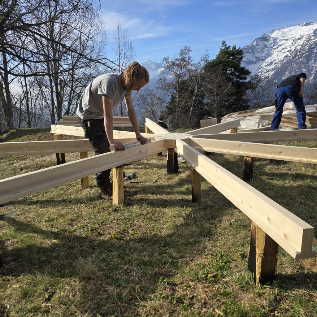 Aufbau der Bodenkonstruktion einer Jurte aus Holz auf Punktfundamenten in der Schweiz.