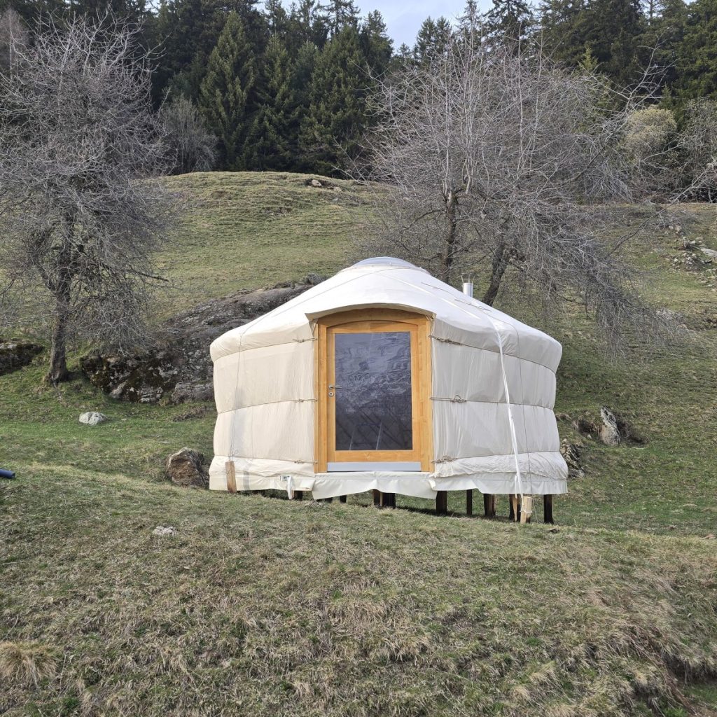 Fertiggestellte handgefertigte Wohnjurte mit Holztüre und natürlicher Isolation in der Schweiz.