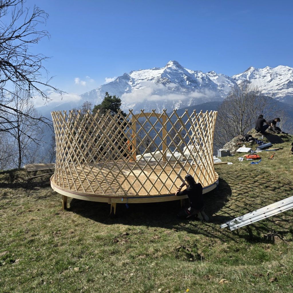 Aufrichten der traditionellen Gitterwände beim Bau einer handgefertigten Wohnjurte in der Schweiz.