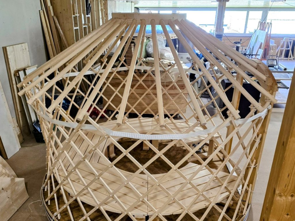 Jurtenrohbau mit Gitterwänden und Dachstangen in der Werkstatt.